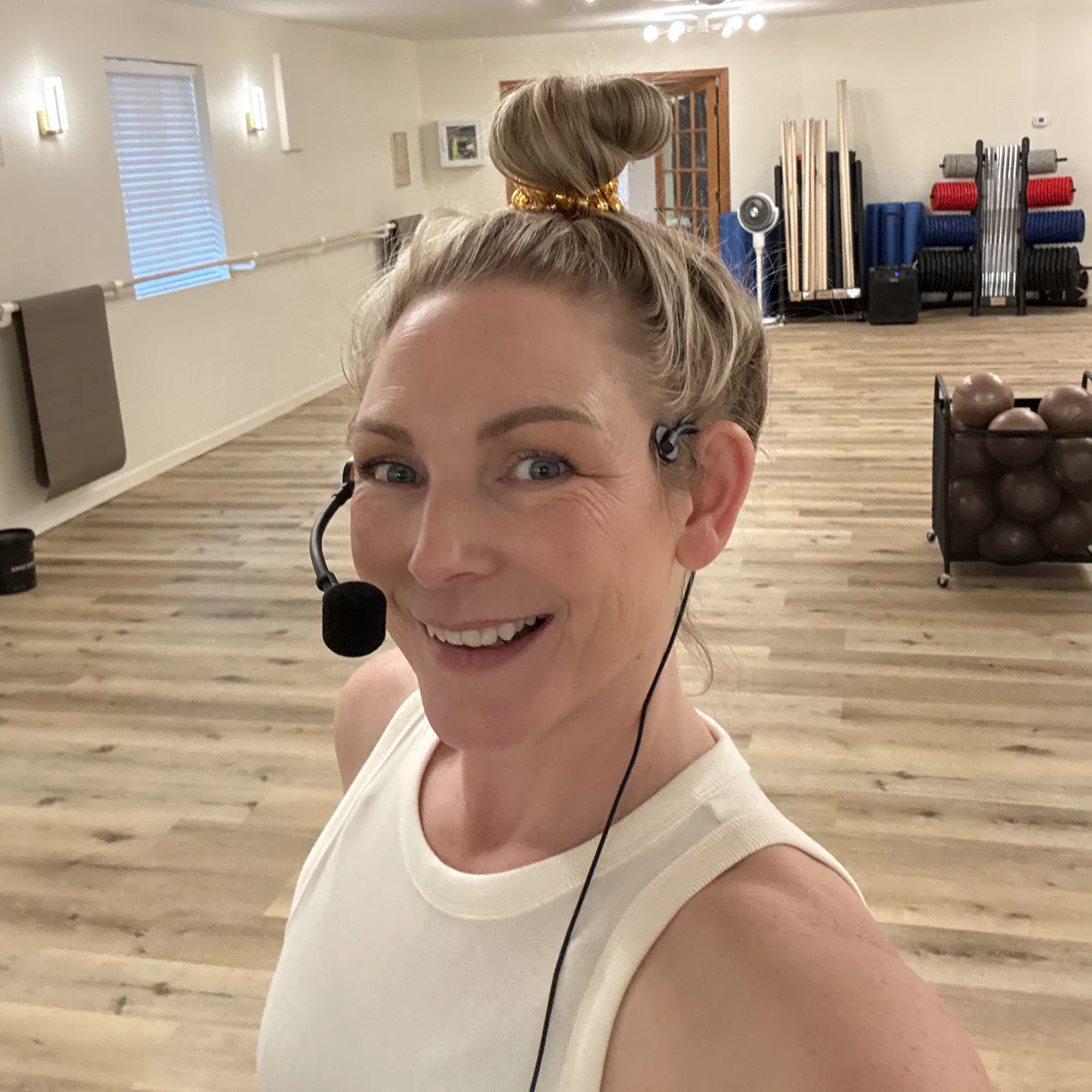 Holly Sanders, owner and personal trainer at Breathe Studio, smiling in the studio wearing a headset before teaching class.