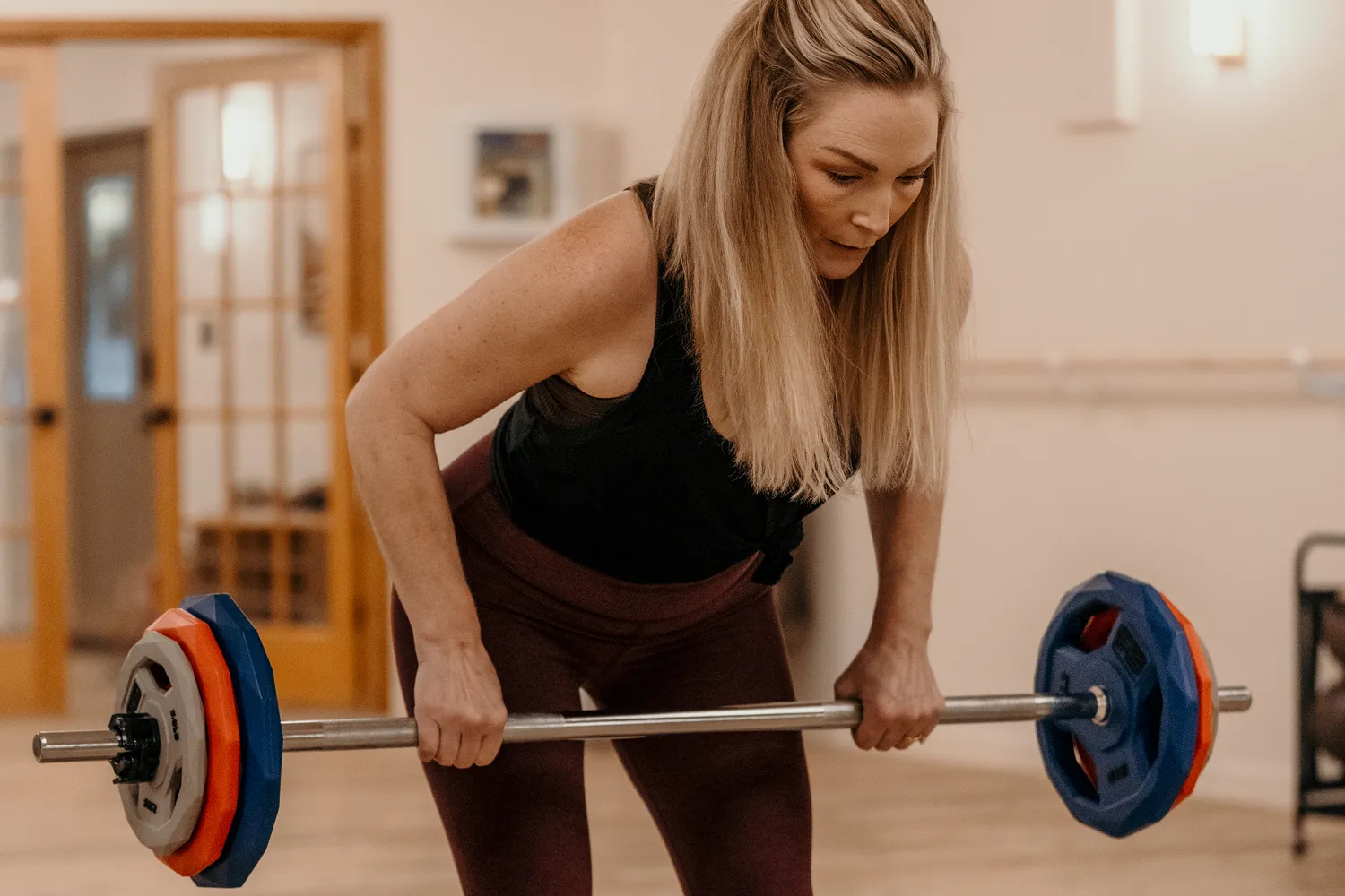 Woman performing a bent-over barbell row during a Pump You Up group strength class.
